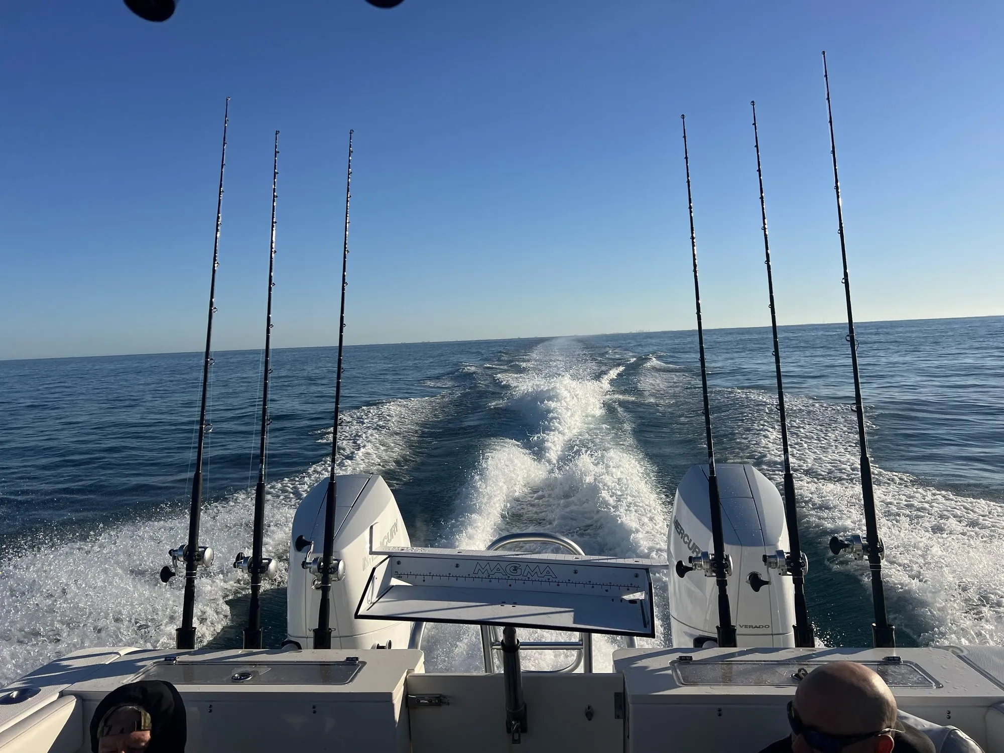 Wake trailing behind Phat Kat with fishing rods lined up across the stern